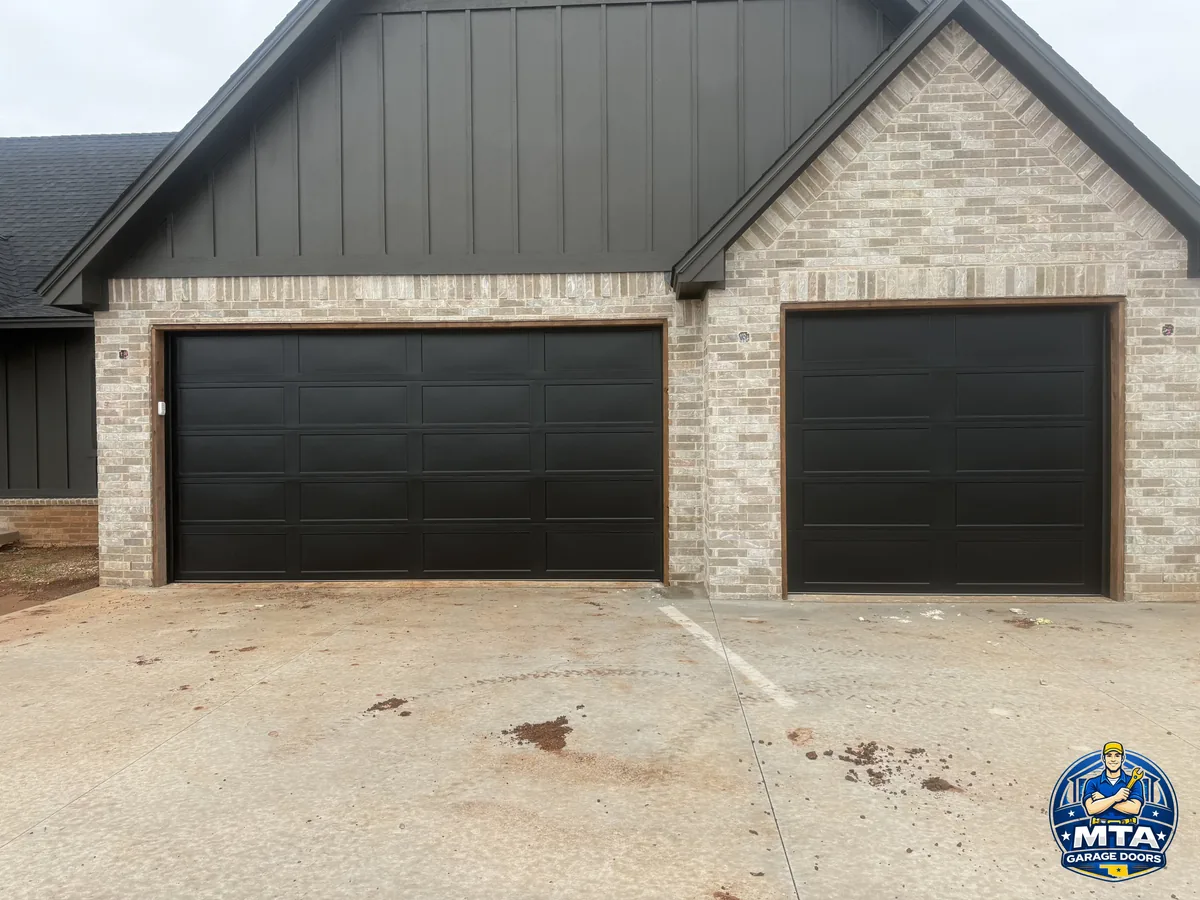 Black double and single sectional garage doors on a brick home