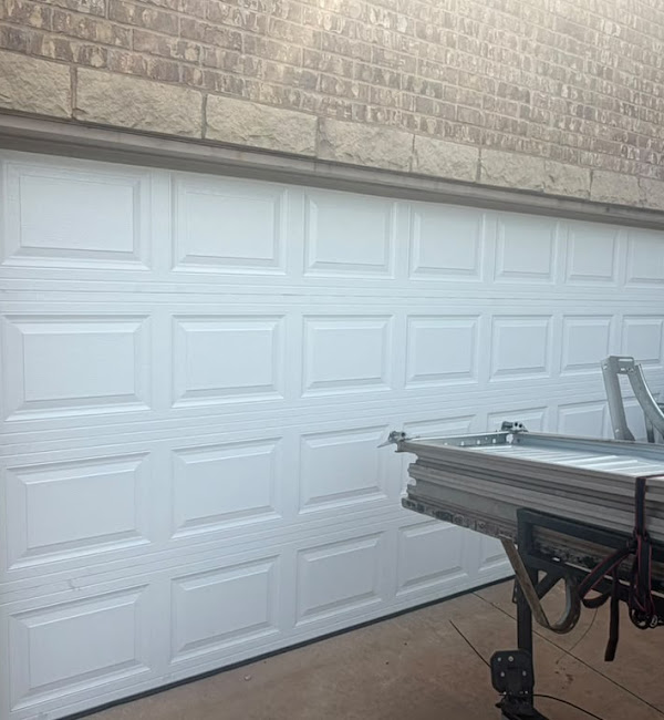 White residential garage door with door sections and installation materials visible in front