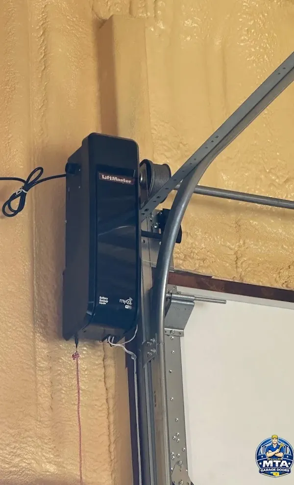 Wall-mounted residential garage door opener beside a torsion shaft