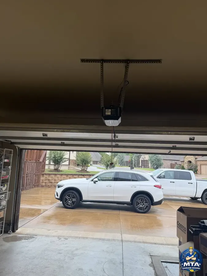 Ceiling-mounted residential garage door opener above an open sectional door