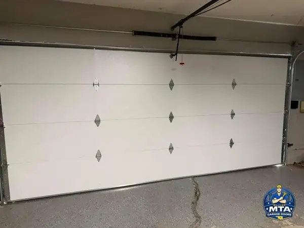 Interior view of a closed residential sectional garage door, tracks, and ceiling-mounted opener
